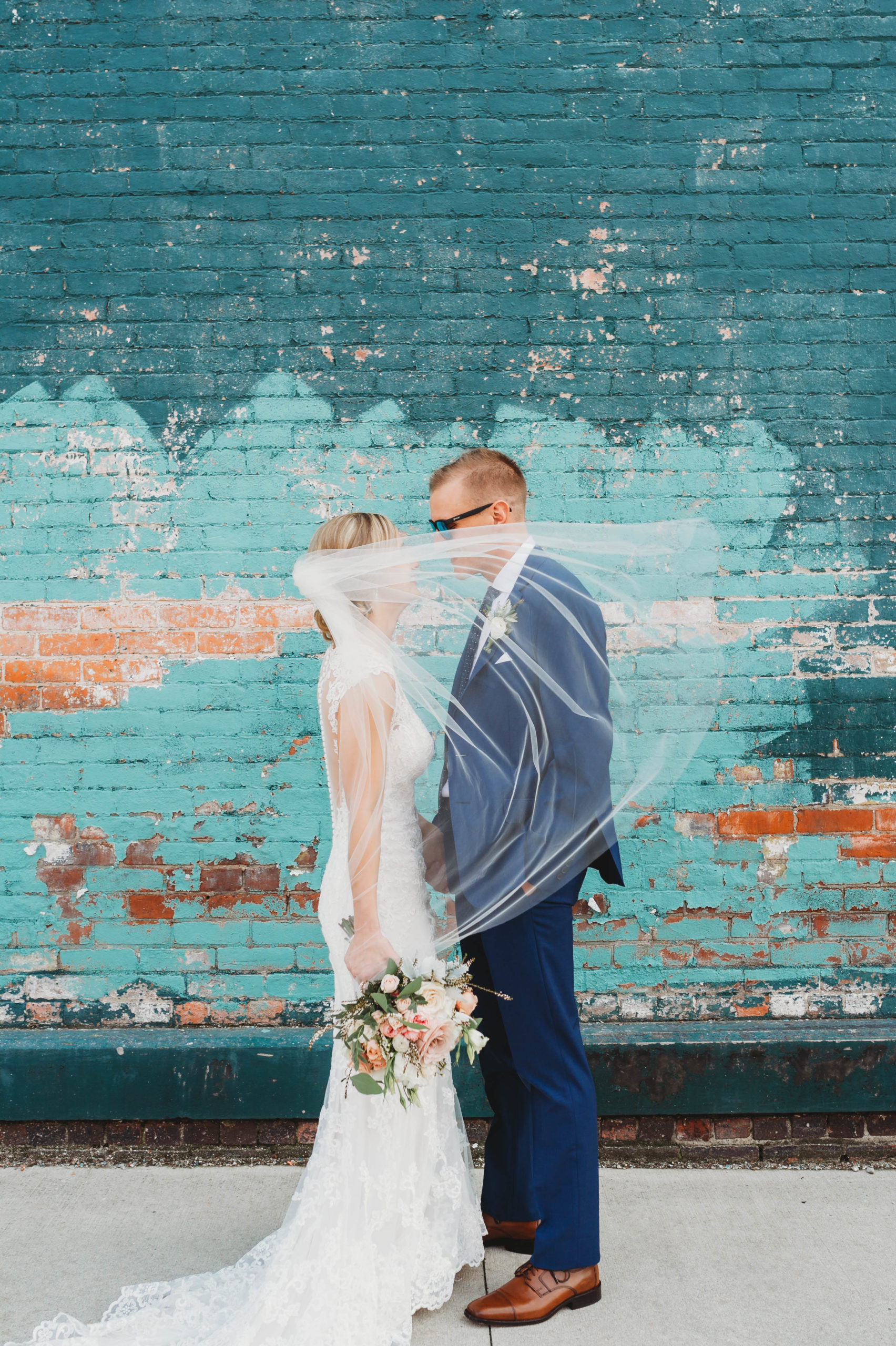 couple poses by teal wall in Ohio