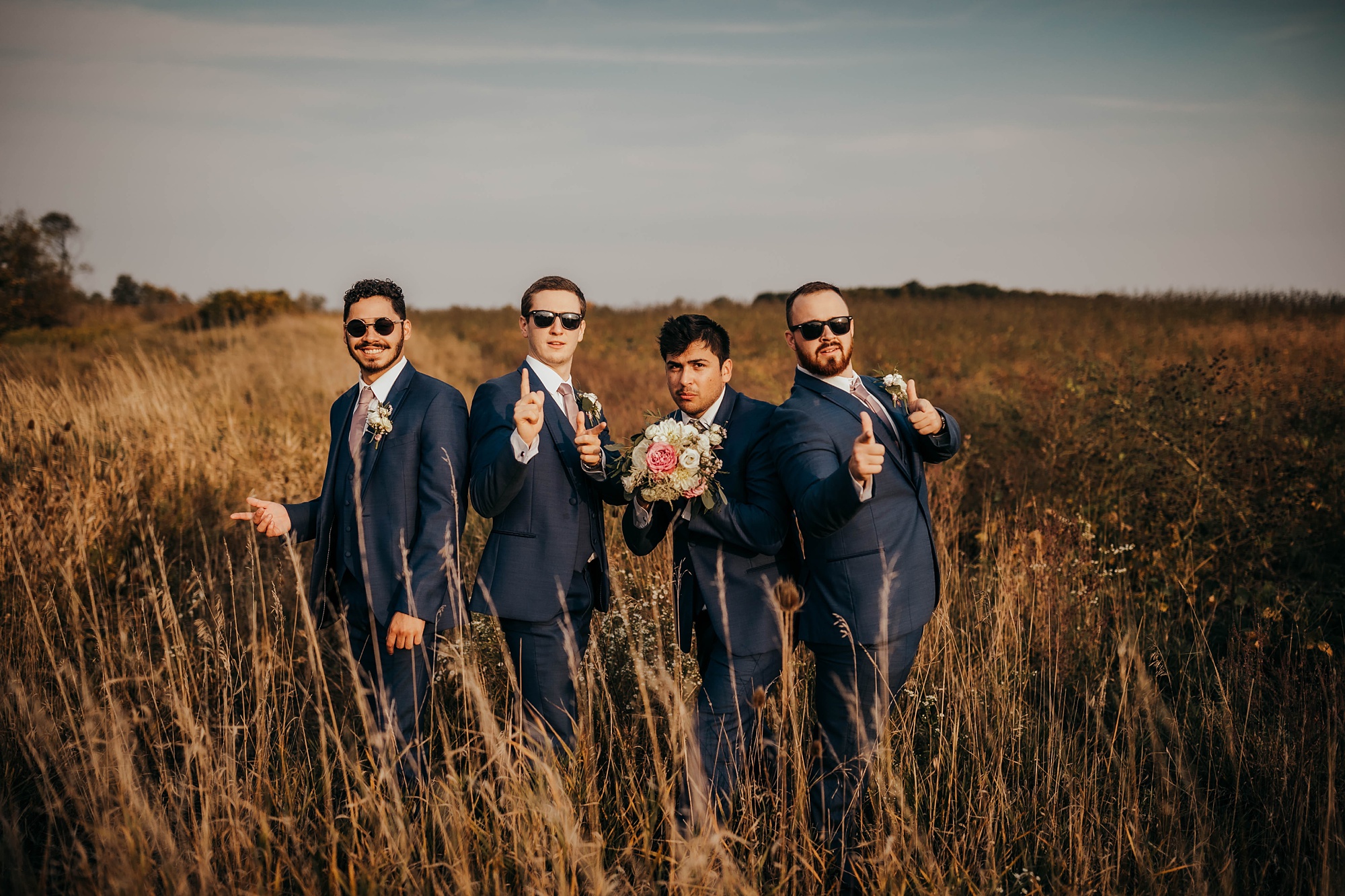 groomsmen pose in the field with sunglasses