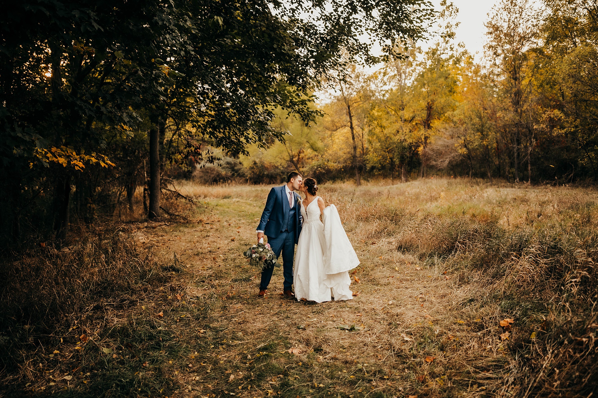 bride and groom kiss in field after elegant fall wedding in Ohio