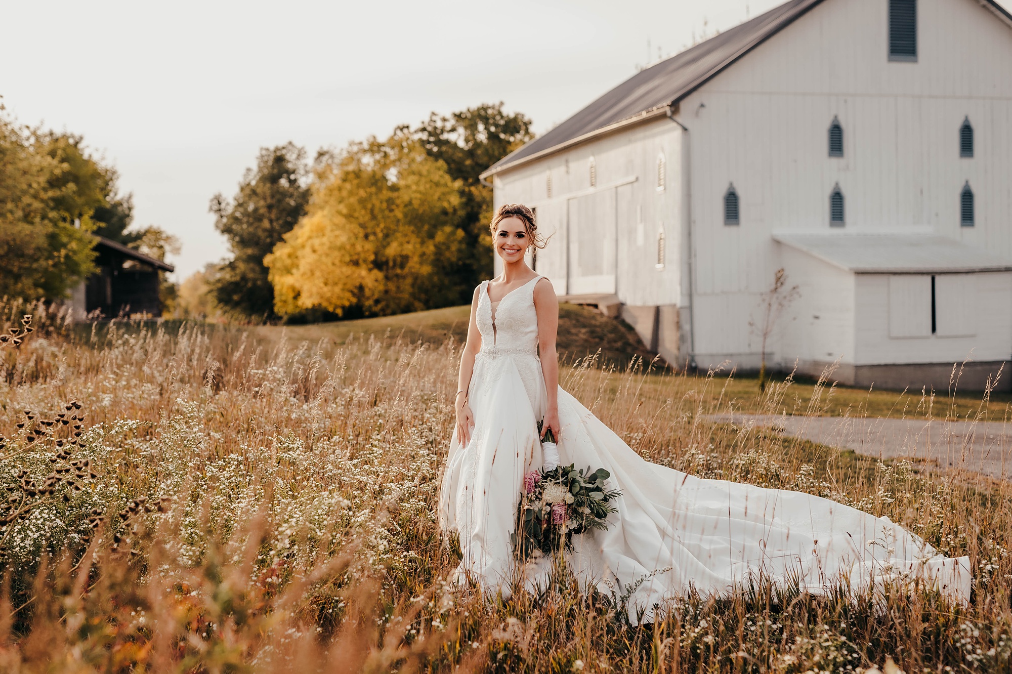 elegant fall bridal portraits in field by barn