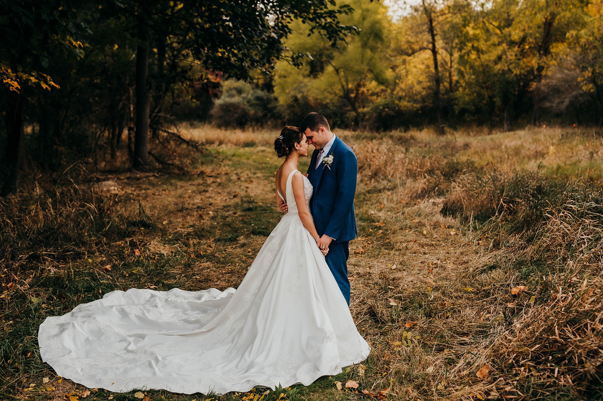 bride and groom stand touching noses in field in Ohio