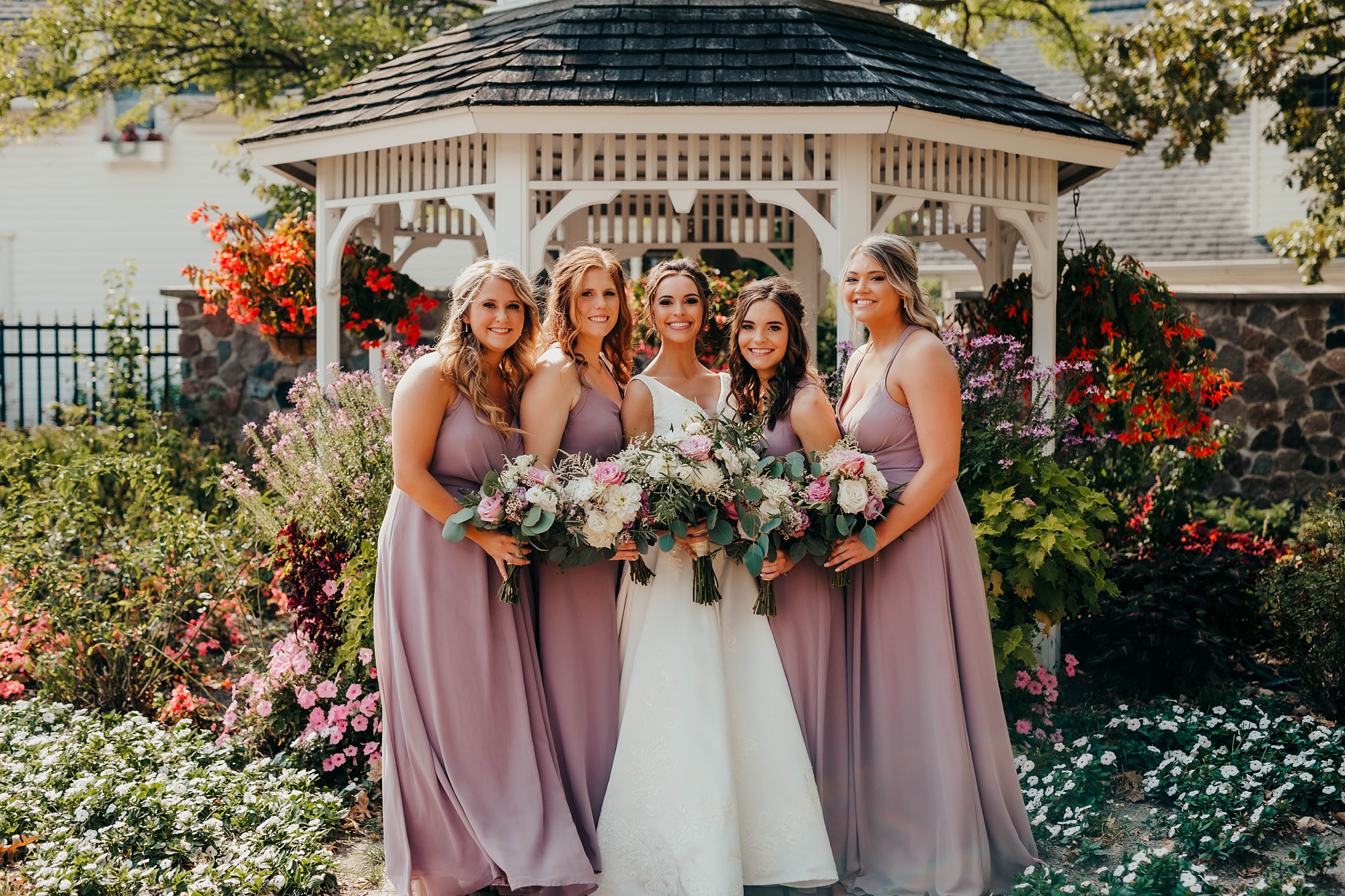 bridesmaids in mauve pose with bride and groom